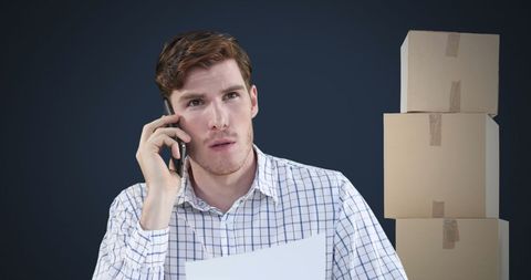 Man Talking on Smartphone Next to Stack of Boxes in Office Setting