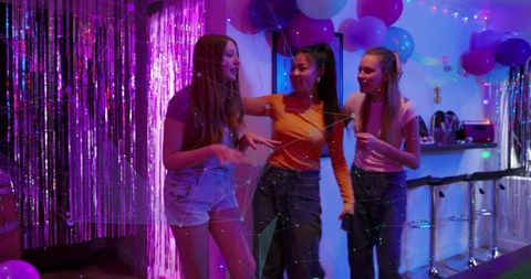 Three friends chatting at neon balloon party with metallic fringe and bar stools