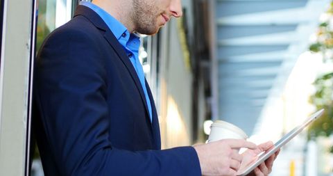 Businessman Using Tablet While Holding Coffee Outdoors - Download Free Stock Images Pikwizard.com