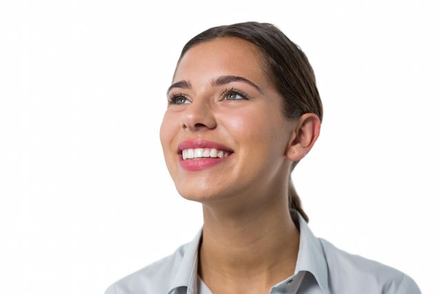 This image shows a young female executive smiling and looking up against a white background. Ideal for use in corporate websites, business presentations, career-related articles, and promotional materials highlighting professional success and positive workplace environments.
