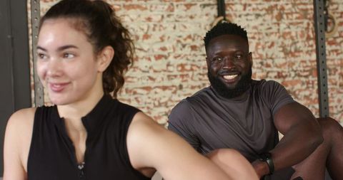 Diverse Workout Partners Relaxing Post-Session in Modern Fitness Studio