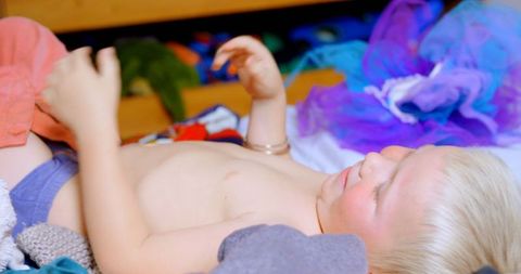 Father Dressing Young Child Amid Colorful Clothing at Home