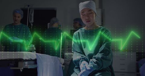 Focused Asian Surgeon with Digital Cardiograph Overlay in Operating Room