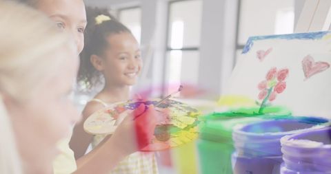 Diverse schoolgirls joyfully painting in art class