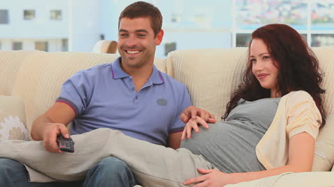 Expectant Couple Enjoying Movie Time on Couch