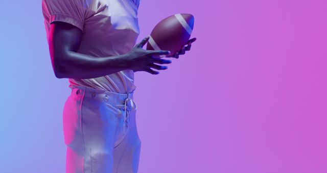 Image of african american american football player with copy space over blue to pink neon background. American football, sports and competition concept.