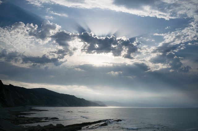 Dramatic Coastal Sunset with Sunrays Through Clouds - Download Free Stock Photos Pikwizard.com