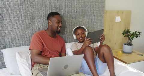 Father and Son Relaxing at Home Using Tablet and Laptop