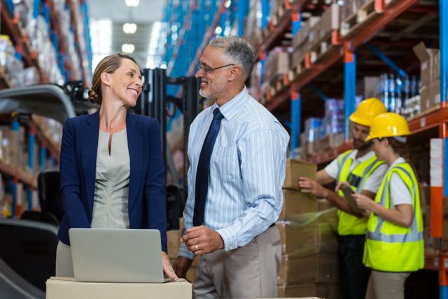 Warehouse manager and client interacting over laptop in warehouse