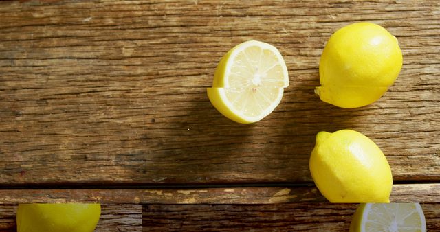 Lemons on a rustic wooden table surface, showcasing freshness and vibrant yellow color. Ideal for use in advertisements for fresh produce, cooking, or health benefits of citrus fruits. Perfect for food blogs, recipe visuals, and wellness articles promoting healthy eating.