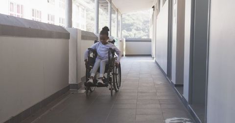 Young African American Girl Navigating Wheelchair in Modern Corridor