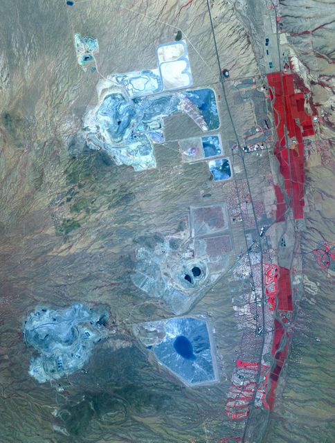 High-resolution satellite image displays several major mining districts approximately 30 km south of Tucson, Arizona, visible with distinct pit mines, leach ponds, and tailings piles. Photo taken by ASTER on May 31, 2012, covers 22 by 28 km area, coordinates 31.9N, 111W. Ideal for studies on resource extraction, earth's surface monitoring, environmental impact analysis, educational content on mining activities, and visual illustrations for geographic, geological seminars.