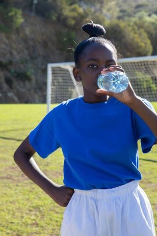 Youthful Soccer Player Staying Hydrated on Field in Bright Sunlight