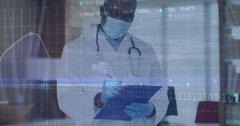 Senior physician reviewing digital patient data on hud while writing on clipboard