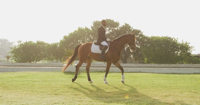 Man is riding horse in an outdoor equestrian competition with bright sunlight. Useful for portraying themes of sport, athletes, leisure activities, and horse riding events. Can be used for articles, equestrian promotional materials, and sporting event advertisements.