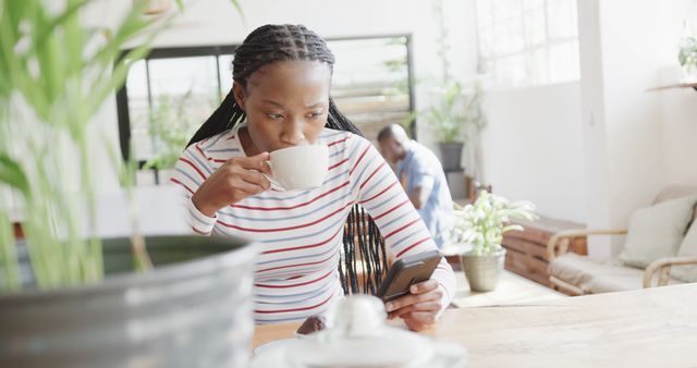 African American Woman Drinking Coffee and Looking at Smartphone in Modern Cafe - Download Free Stock Images Pikwizard.com