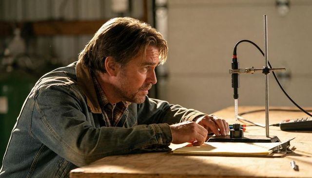 Technician adjusting probe and testing liquid sample on workbench in rustic garage lab