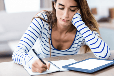 woman in striped shirt writing next to a transparent tablet - Download Free Stock Videos Pikwizard.com