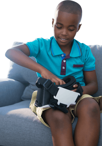 Young boy engaging with virtual reality viewer on couch transparent