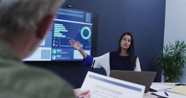Female professional presenting data analysis using large screen during business meeting. Suitable for depicting corporate environments, teamwork, strategic planning sessions, financial reporting, and business analytics presentations.