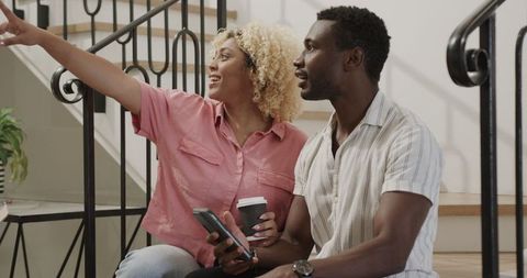 Smiling Couple Enjoying Coffee on Staircase at Home