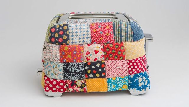 Colorful patchwork quilted toaster cozy cover protecting stainless steel two-slice toaster