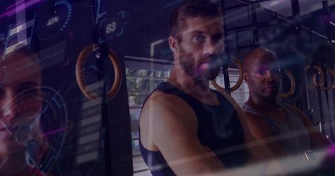 Two male athletes standing with arms crossed in gym with futuristic hud overlay for training