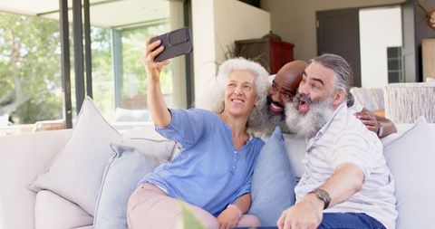 Happy Senior Friends Relaxing and Taking Selfie on Sofa