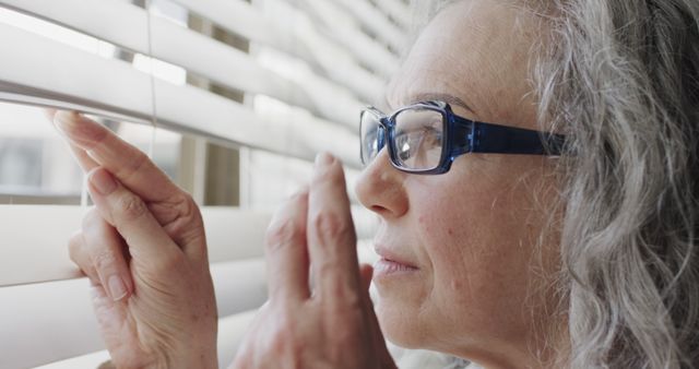 Senior Woman Peering Through Blinds with Serious Expression - Download Free Stock Images Pikwizard.com