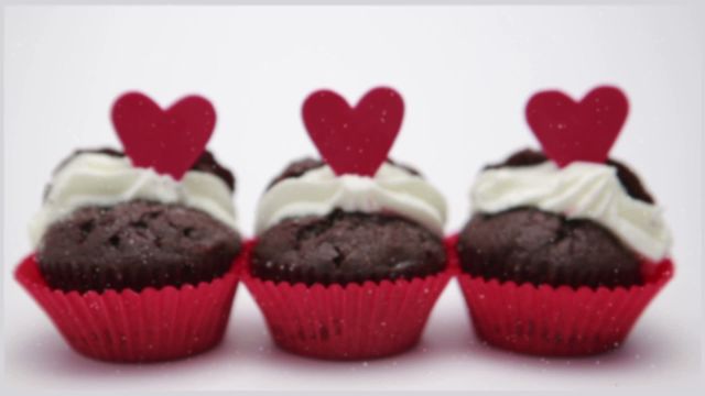 Charming Valentine's Day cupcakes arranged with vibrant red heart toppers and decorated with whipped cream. Ideal for use in cooking blogs, romantic holiday promotions, or festive event marketing materials. This image captures the spirit of celebration and affection, perfect for Valentine's theme presentations or invitations.