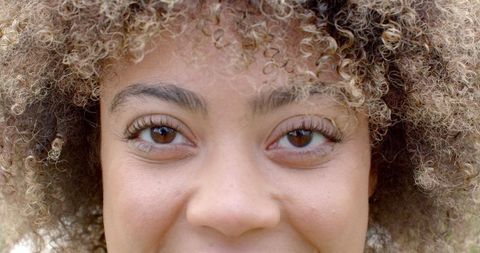 Close-Up of Smiling Young Woman with Curly Hair Capturing Joyful Expression