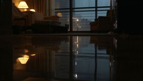 Warm Lamp Reflections on Polished Floor in Cozy Living Room Overlooking Rainy City Lights