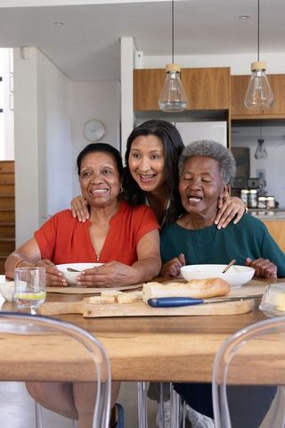 Multigenerational african american women sharing meal around kitchen table, family moment
