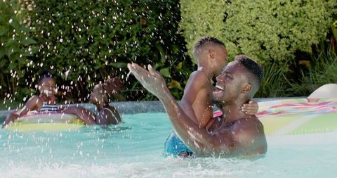 Father enjoying summertime with son in backyard pool