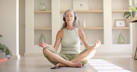 Senior Woman Meditating with Headphones in Bright Living Room