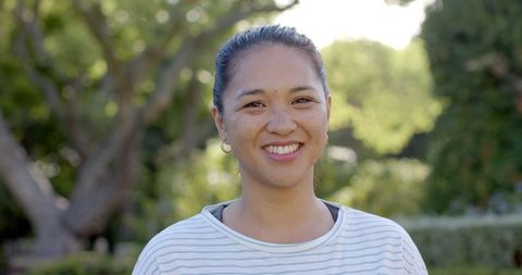 Smiling Woman Enjoying Sunshine in Lush Green Park