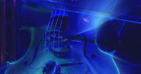 Blue teal stage cello closeup showing f-holes and strings under concert lighting