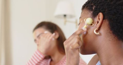 Diverse friends using yellow facial roller for glowing skin home spa routine