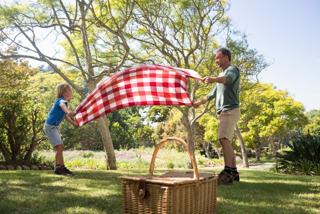 Father and son spreading the picnic blanket in the park