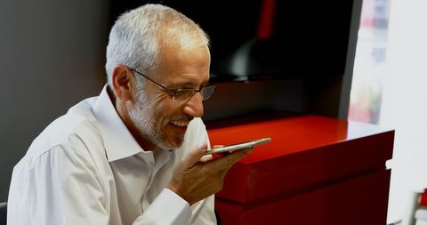 Mature businessman using voice command on smartphone