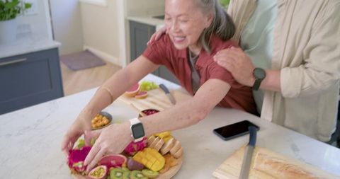 Couple preparing colorful fruit platter using ar recipe tags on kitchen island