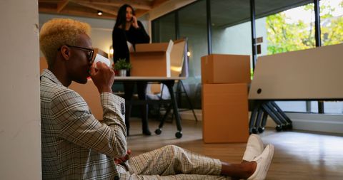 Young Businessman Relaxing with Coffee in Busy Office Environment