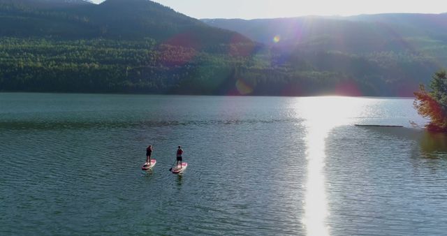 Two People Paddleboarding on Serene Lake at Sunset - Download Free Stock Images Pikwizard.com