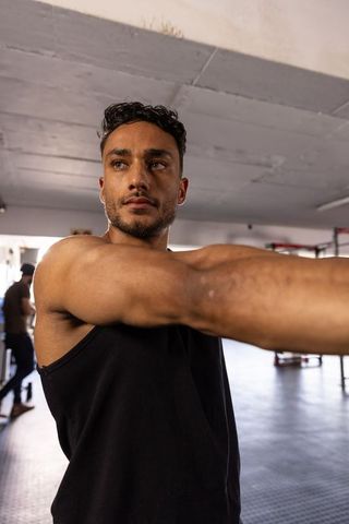 Focused Athlete Practicing Arm Stretching in Gym Environment