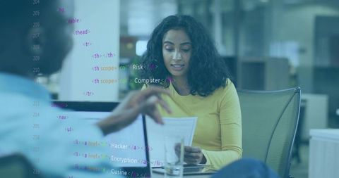 Woman reading documents during office meeting, laptop open, code overlay showing analytics