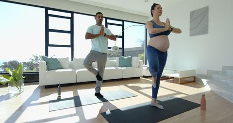 Diverse Couple Practicing Yoga Tree Pose at Home in Natural Light
