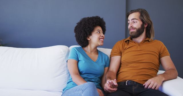Portrait of biracial couple holding hands while sitting on the couch at home - Download Free Stock Photos Pikwizard.com