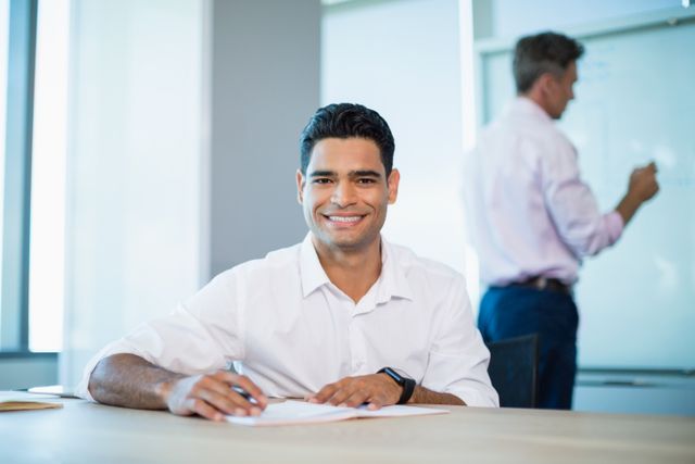 Portrait of smiling business executive writing on notebook in conference room at office