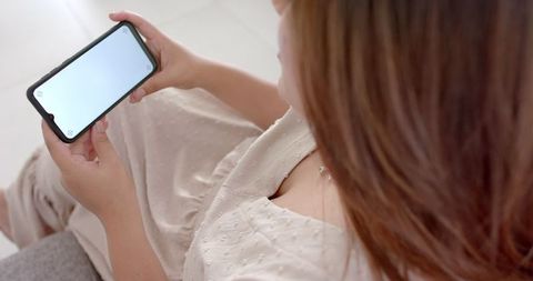 Woman barness smartphone at home with blank screen wering