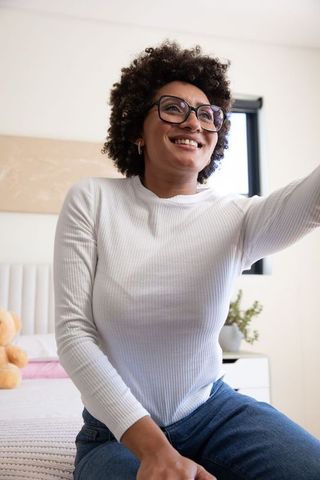 Smiling woman in cozy bedroom reaches for teddy bear
